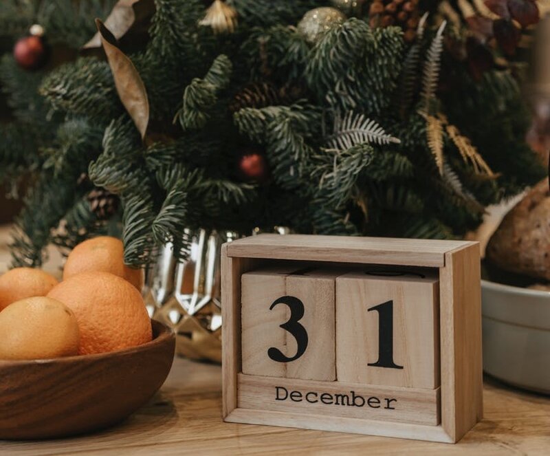 Decorazioni natalizie, una ciotola di legno con limoni e un calendario in legno che indica il 31 dicembre