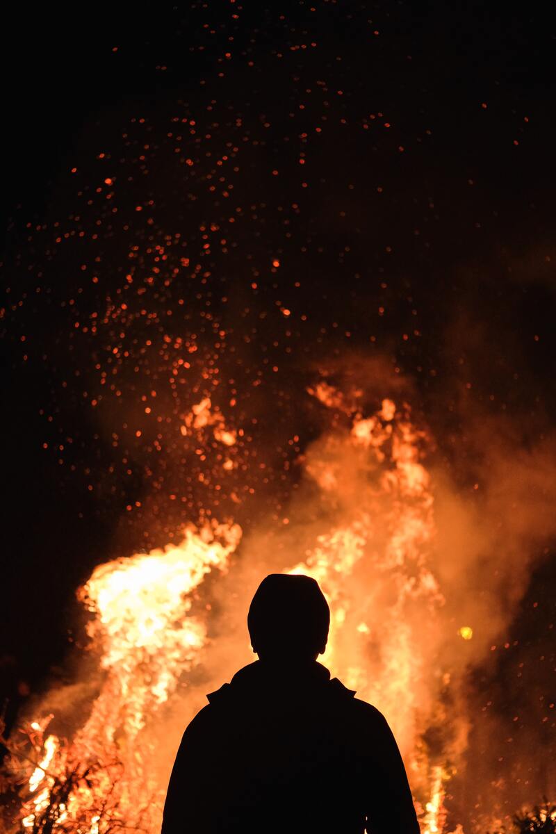 La silhouette di un uomo che osserva un incendio 